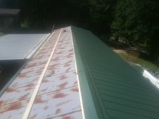Old rusted panels beside newly installed green metal roofing — Wind Damage Roof Repair by Roofing Brothers in Mont Vernon