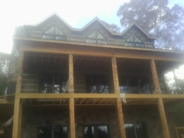 Dormers and porch framing on a large log home under construction — Roof Coating work by our crew in Mont Vernon