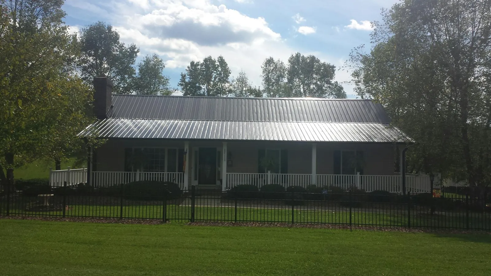 Gray metal roof on a brick ranch with a full width front porch — Gutter Guard Installation work by our crew in Mont Vernon
