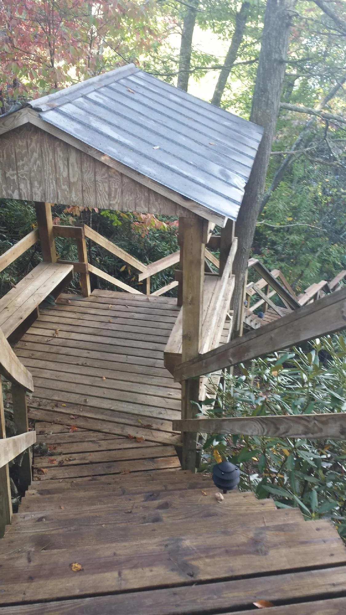 Metal roofed shelter over wooden steps on a wooded walkway — Skylight Repair & Installation work by our crew in Mont Vernon