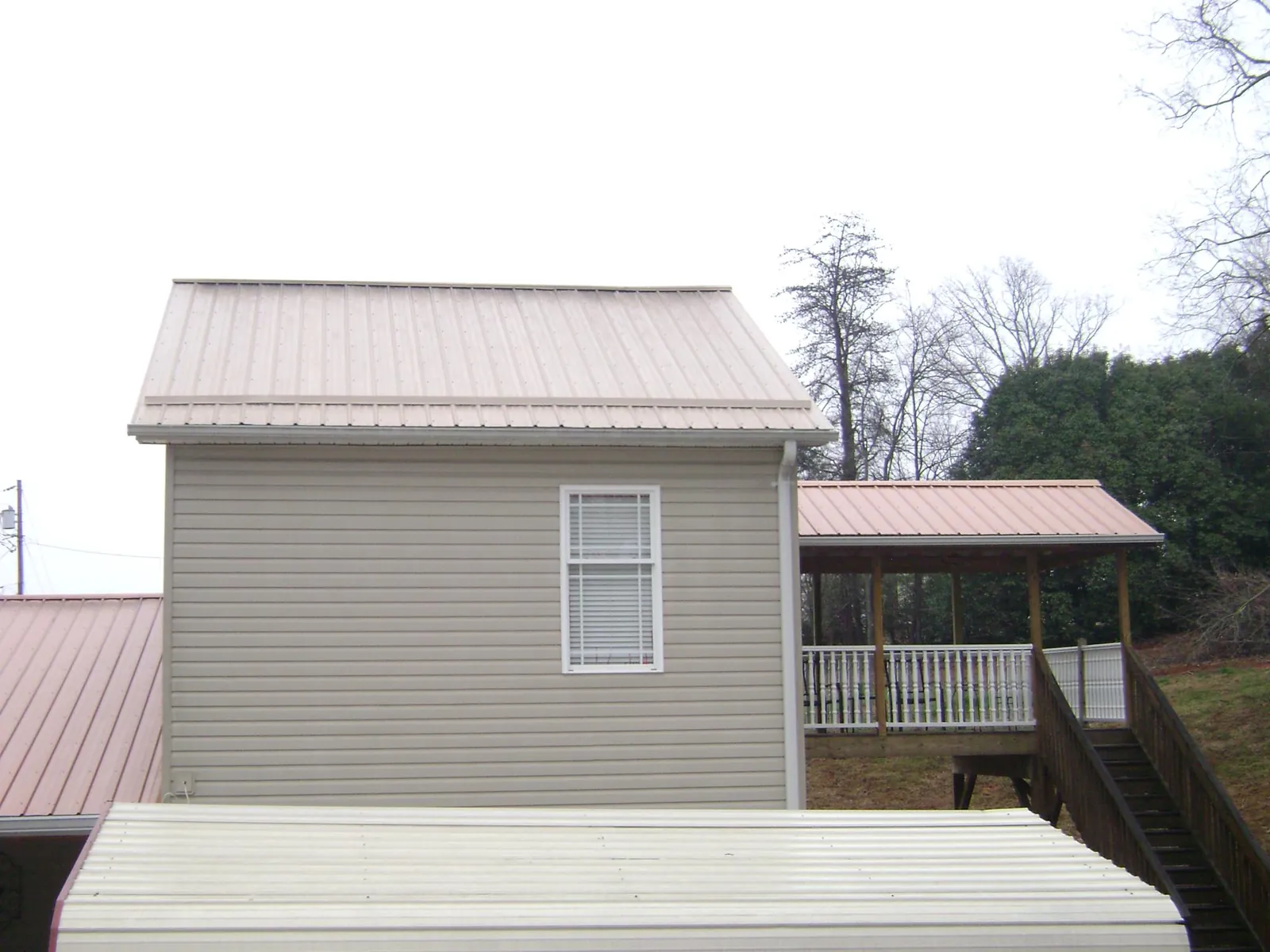 Tan metal roofs on a two story addition and attached porch, from a Roof Replacement job in Mont Vernon